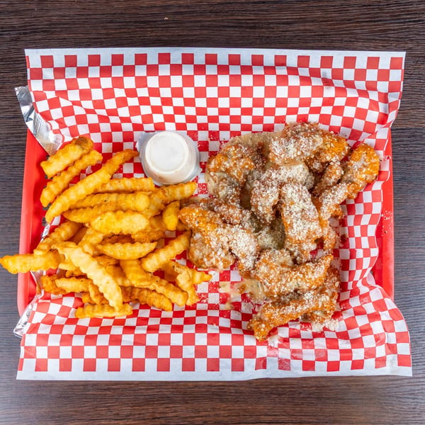Basket of crinkle-cut fries and powdered-sugar-dusted fried chicken tenders with dipping sauce on red-and-white checkered paper.